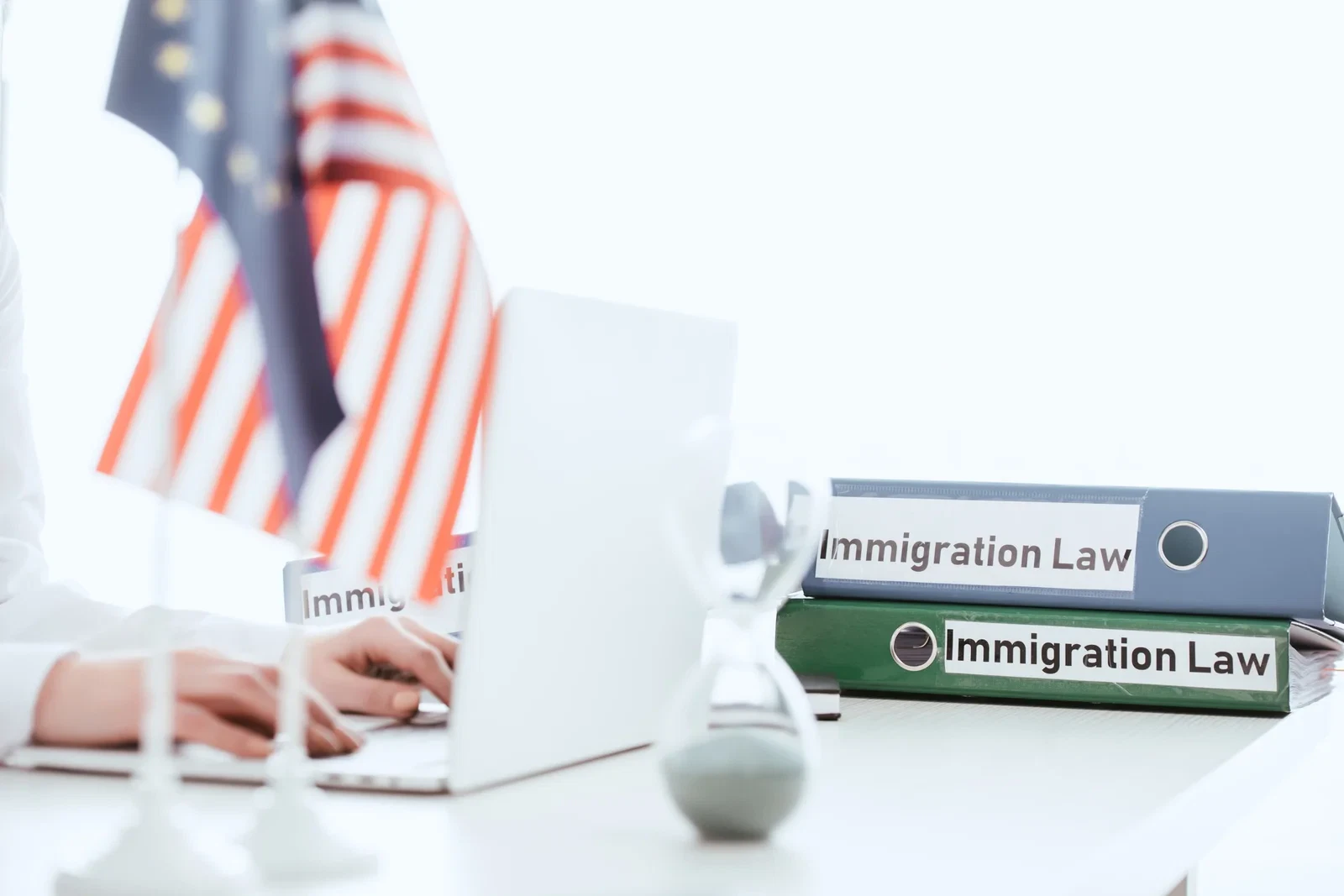 selective focus of woman typing on laptop near hourglass and american flag